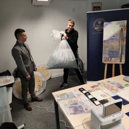 Chłopiec podnosi worek ze zniszczonymi pieniędzmi o wartości jednego miliona.