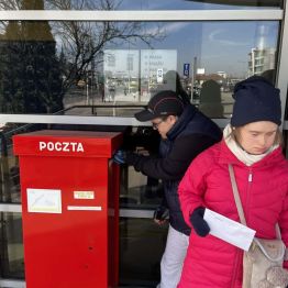 Dawidek wrzuca list do skrzynki. Kasia czeka, żeby wrzucić swój list.