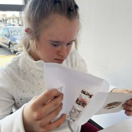 Kasia siedzi i chowa wpisane życzenia do koperty.