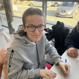 Malwinka siedzi i pisze życzenia.