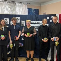 Absolwenci pozuję do zdjęcia z upominkami od kolegów.