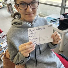 Malwinka trzyma w rękach widokówkę, na której sama napisała pozdrowienia dla rodziców.