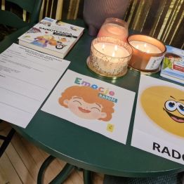 Na zdjęciu widać stolik z książkami o bajkoterapii, kartką graficzną z napisem RADOŚĆ.