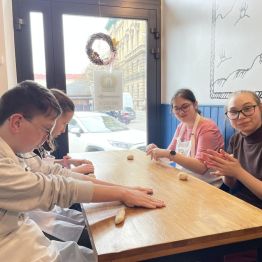 Trzy dziewczynki i chłopiec wyrabiają ciasto na obwarzanki.