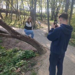 Wychowanek robi zdjęcie koleżance przy drzewie.