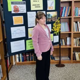 Dziewczynka recytująca wiersz w szkolnej bibliotece.