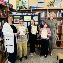 Laureaci konkursu z klas I-III SP z Paniami Dyrektor. W tle regały z książkami.