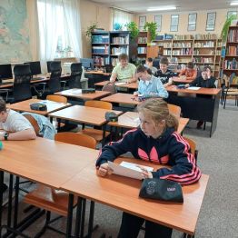 Uczniowie siedzą przy stoliku i piszą pracę konkursową