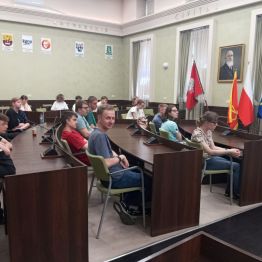 Uczniowie siedzą w sali obrad i słuchają pani prezydent