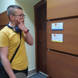 uczeń stoi przy drzwiach w Urzędzie Miasta Kielce i zastanawia się gdzie załatwi daną sprawę urzędową