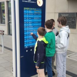 Chłopcy stoją przy rozkładzie jazdy pociągów