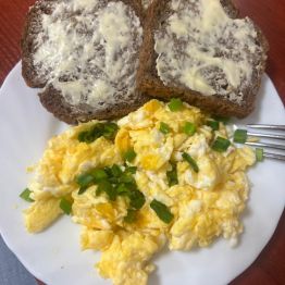 Jajecznica z gęsich jaj ze szczypiorkiem i ciemnym pieczywem z masłem.