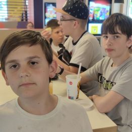 Jeden chłopiec stoi i dwóch je obiad przy stole