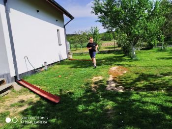 Uczeń biegnie po trawie, obok dom