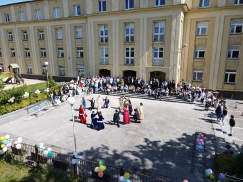 Uczniowie tańczą poloneza przed szkołą