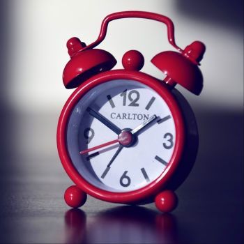 Czerwony zegarek ba szarym stole.