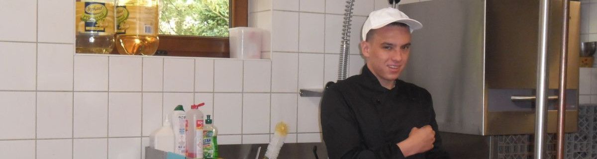 Uczeń w fartuchu i czapce w kuchni.