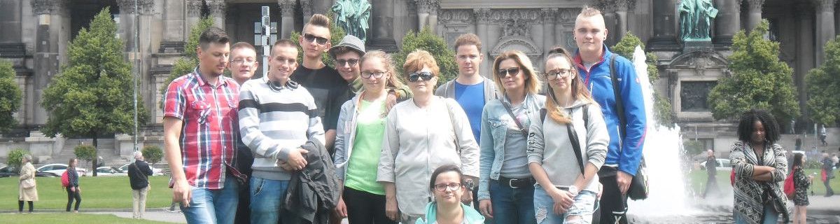 Grupa uczniów stojących przed fontanną.