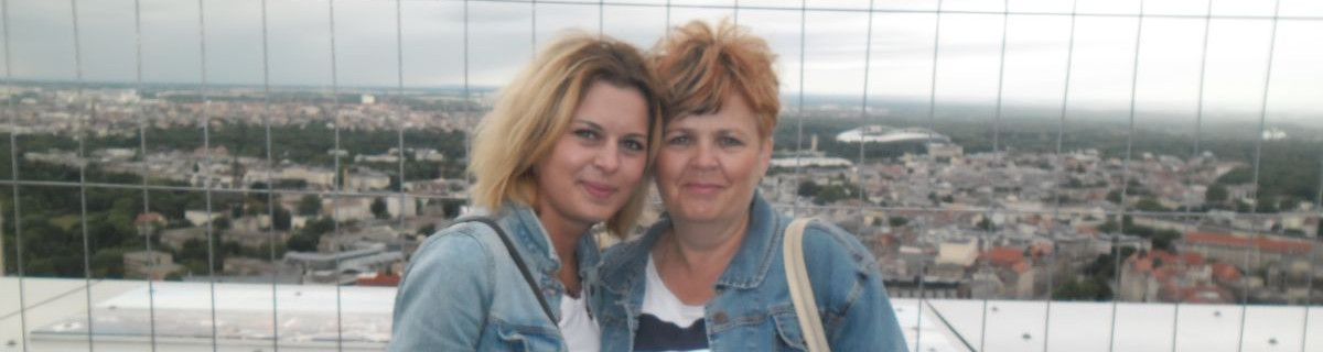 Dwie nauczycielki uśmiechają się, za nimi panorama miasta