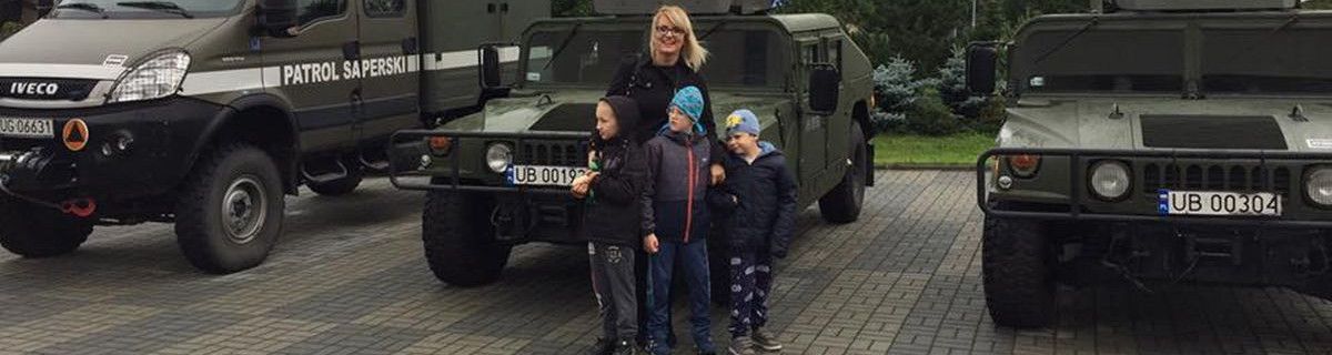 Pani pedagog i uczniowie stoją przed wojskowymi pojazdami