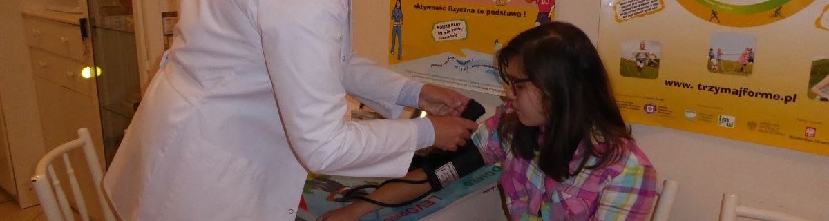 Szkolna pielęgniarka mierzy ciśnienie uczennicy