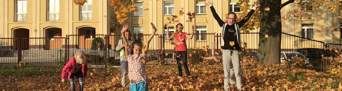 Grupka dzieci podrzucających jesienne liście
