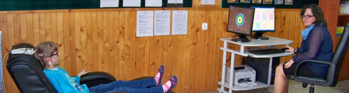 Uczennica na zajęciach EEG Biofeedback. Dziewczynka leży na fotelu przed ekranem monitora.