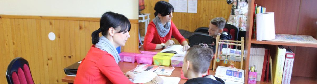 Logopeda siedzi z uczniem przed lustrem.