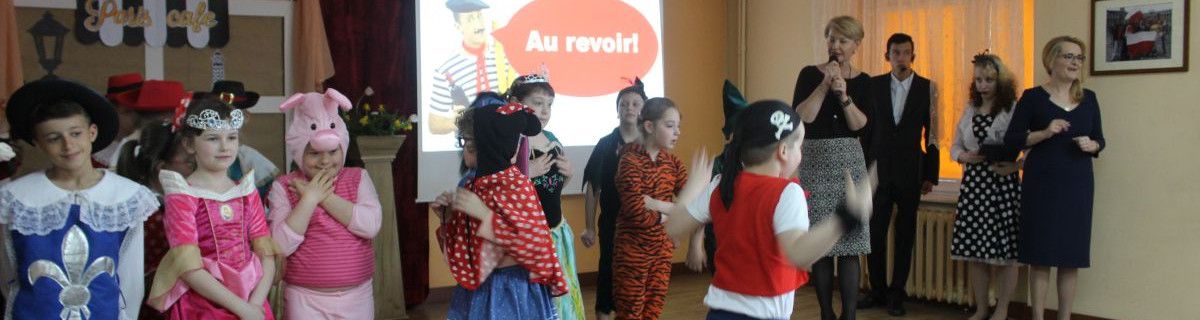 Grupka uczniów w strojach bohaterów z bajek stoi na scenie
