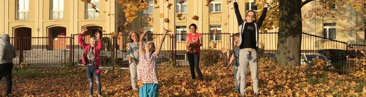 Grupa dzieci podrzucających jesienne liście