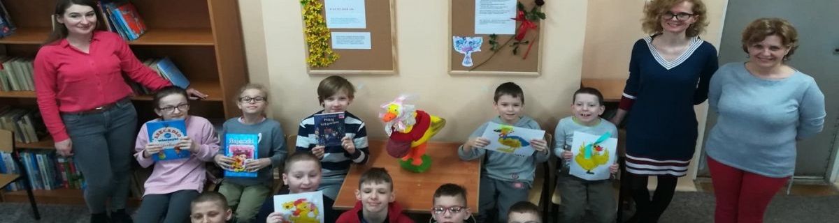 Grupka uczniów trzymających książki, obok bibliotekarka i nauczycielki