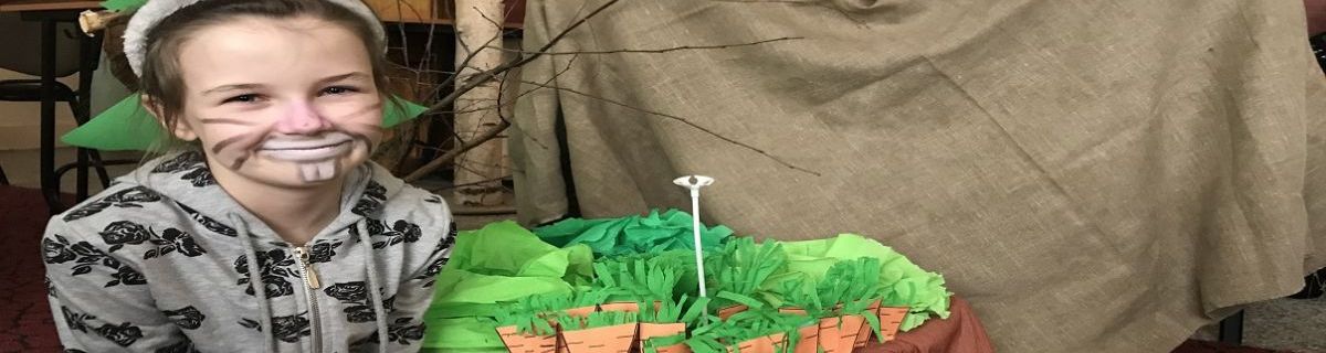 Dziewczynka przebrana za zająca kuca pod dekoracjami z przedstawienia