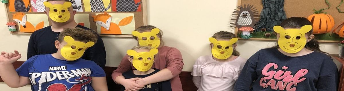 Grupa uczniów w żółtych maskach w kształcie misiów