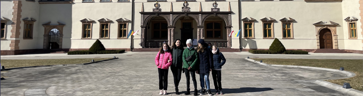 Grupka uczniów i nauczycielka przed wejściem do muzeum.