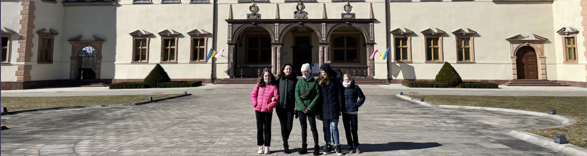 Grupa uczniów i nauczycielka przed wejściem do muzeum.