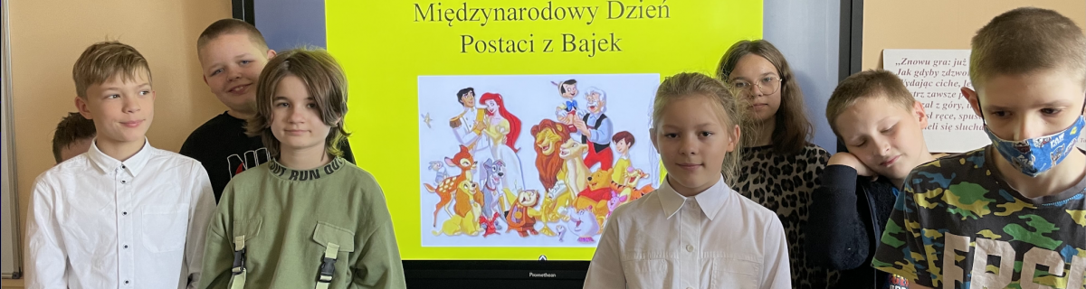 Uczniowie przed tablicą z napisem "Międzynarodowy Dzień Postaci z Bajek".