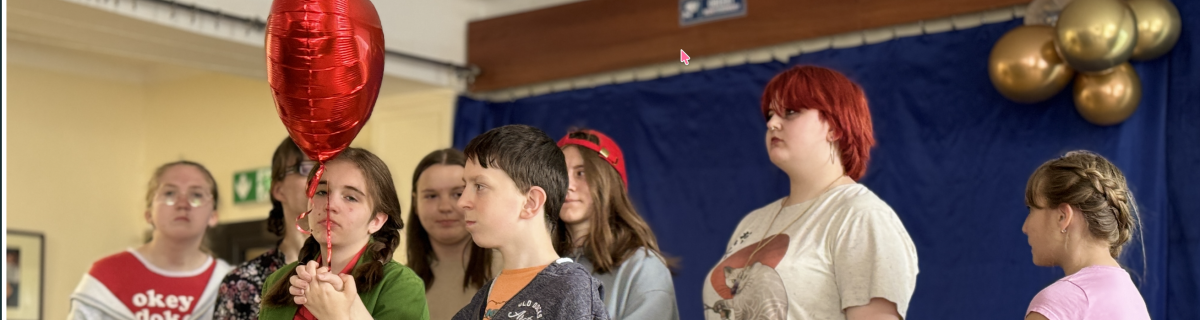  Uczniowie na scenie trzymają czerwony balonik 