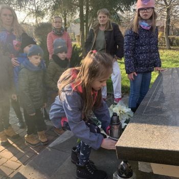 Uczennica z klasy I c składa znicz przy pomniku upamiętniającym ofiary okupacji.