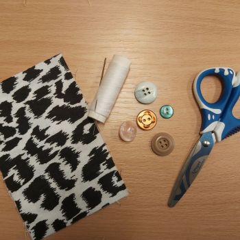 Przygotowanie materiałów do przyszycia guzików: igła, nitka, kawałek materiału,  guzki i nożyczki.