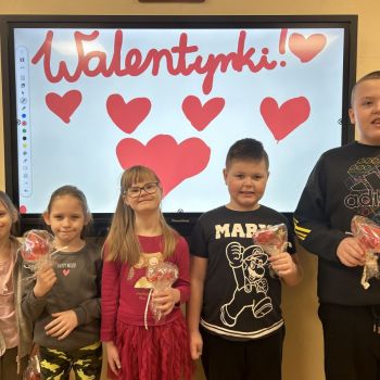 Uczniowie klasy 1 c, stoją przed tablicą walentynkową ze swoimi upominkami.