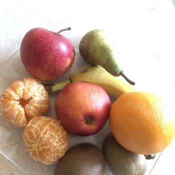 Na stole leży talerz z owocami.