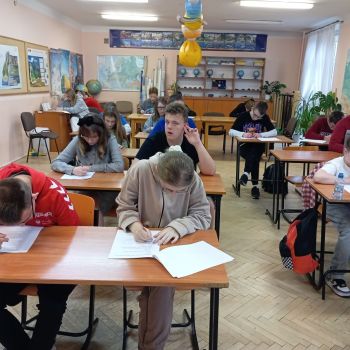 Uczniowie siedzą w ławkach i piszą Konkurs