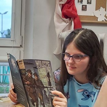 Dziewczynka czyta komiks o II wojnie światowej. 