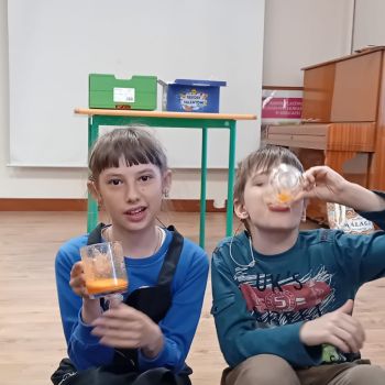 Dziewczyna trzyma szklankę z sokiem, chłopiec pije sok