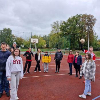 Wychowankowie stoją w kole, przygotowują się do rozgrzewki. Chłopiec trzyma piłkę w ręce.