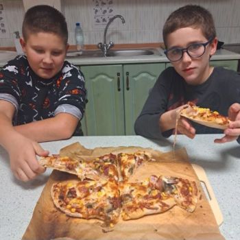 Chłopcy konsumują swoją pizzę.