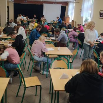 Uczniowie siedzą przy stoliku i piszą pracę konkursową