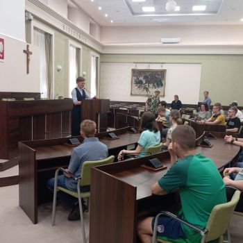 Uczniowie siedzą w sali obrad i słuchają pani prezydent