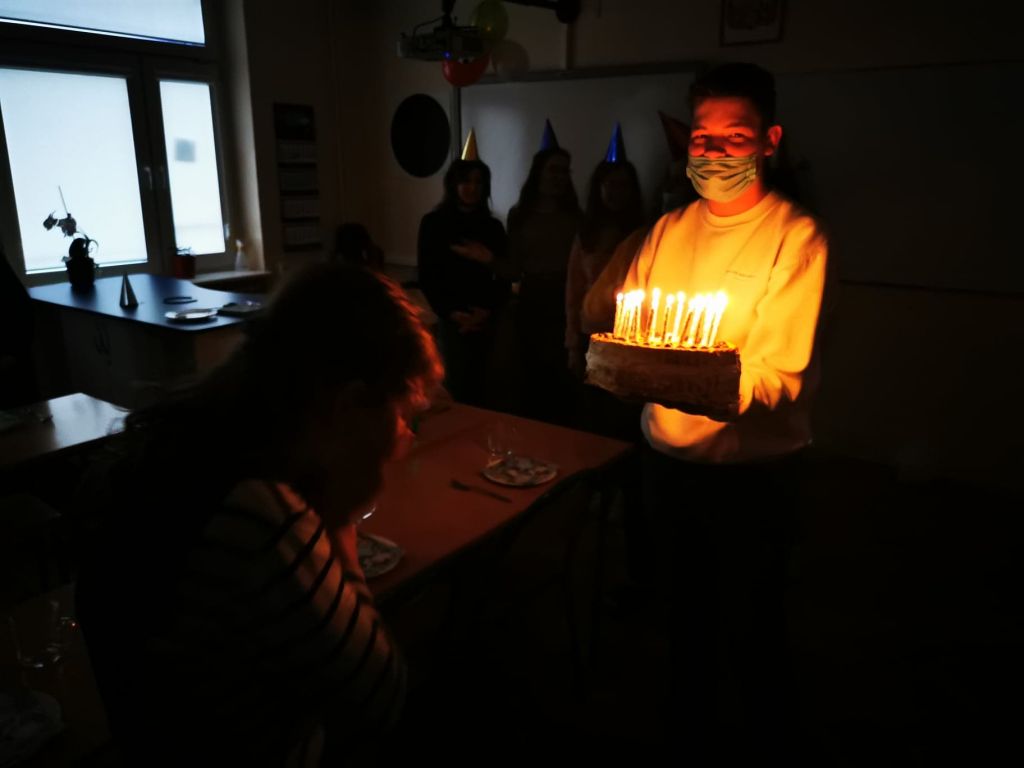 Uczeń w maseczce na twarzy podaje koleżance tort
