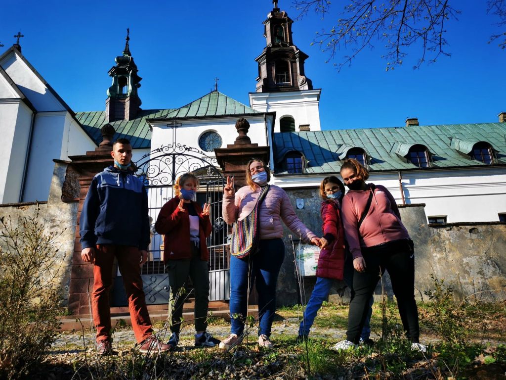 Grupa uczniów stoi przed bramą prowadzącą do kościoła